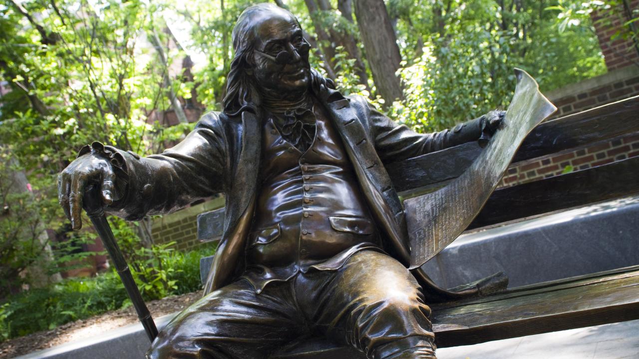 ben franklin on a bench statue on penn campus